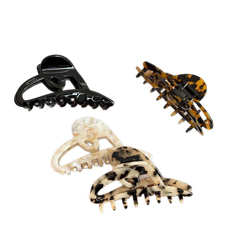 Five acetate claw clips in black, tortoise, cream, and brown patterns with heart-inspired cutouts