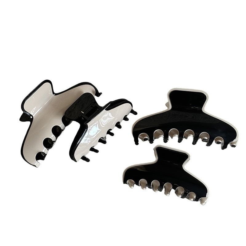 Minimalist acetate claw clip in glossy cream and black tones on a white background