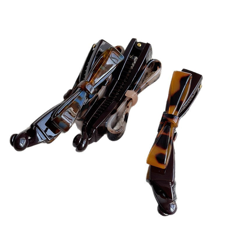 Three patterned cellulose acetate bow twist hair clips in tortoise and floral finishes