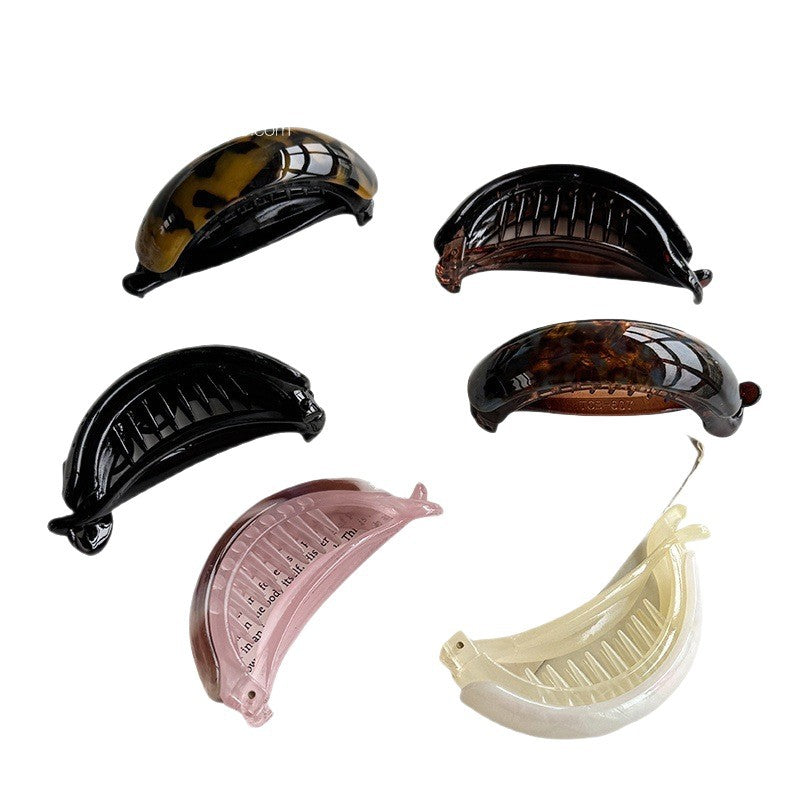 Set of six cellulose acetate banana hair clips in black, tortoise, floral, pearl brown, and mermaid finishes on a white background
