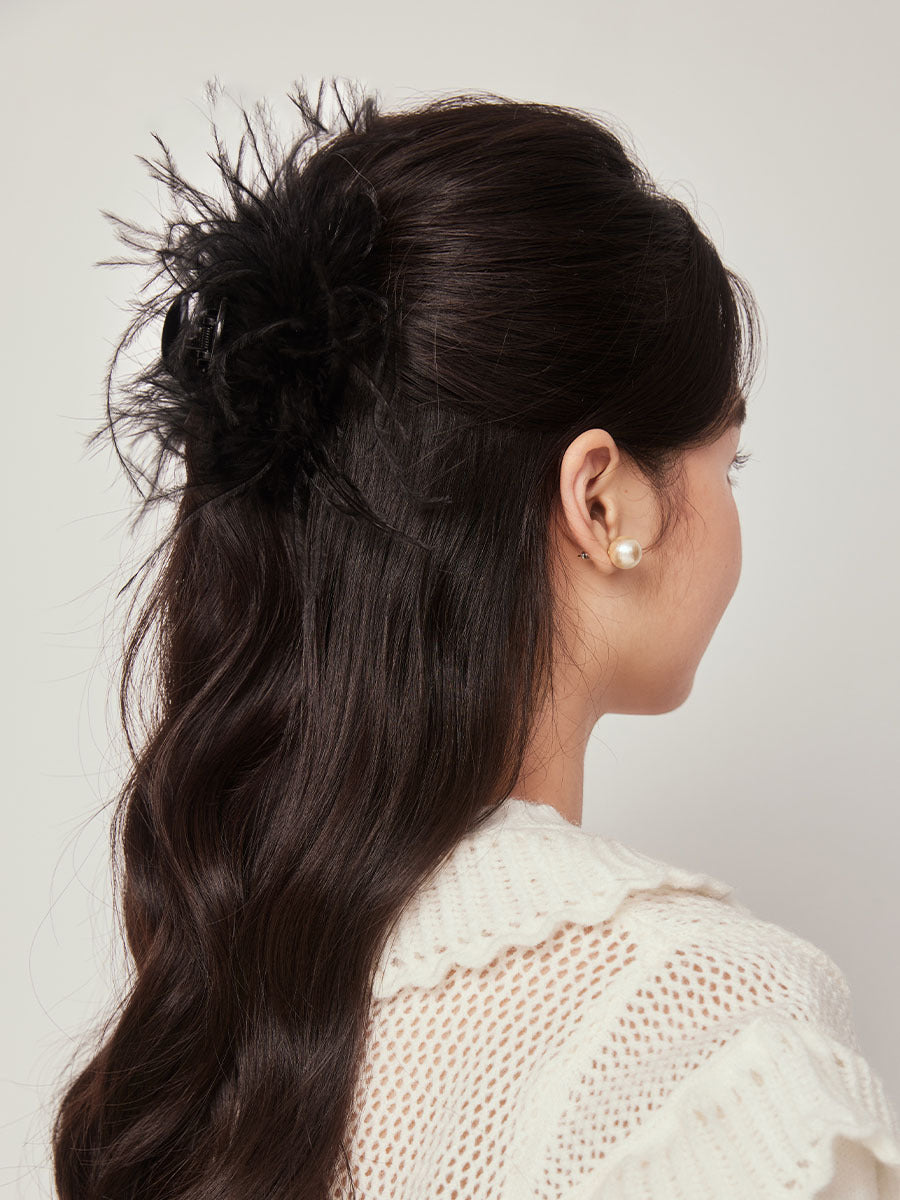 Rear view of dark hair styled with a black feather claw clip