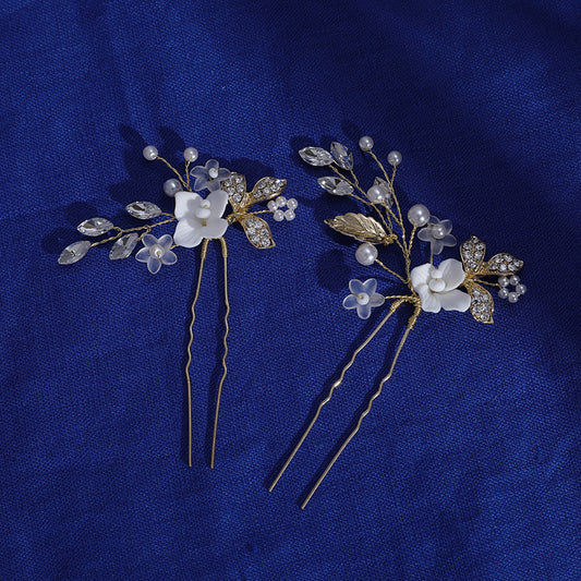 Pair of floral hair pins shown on blue fabric