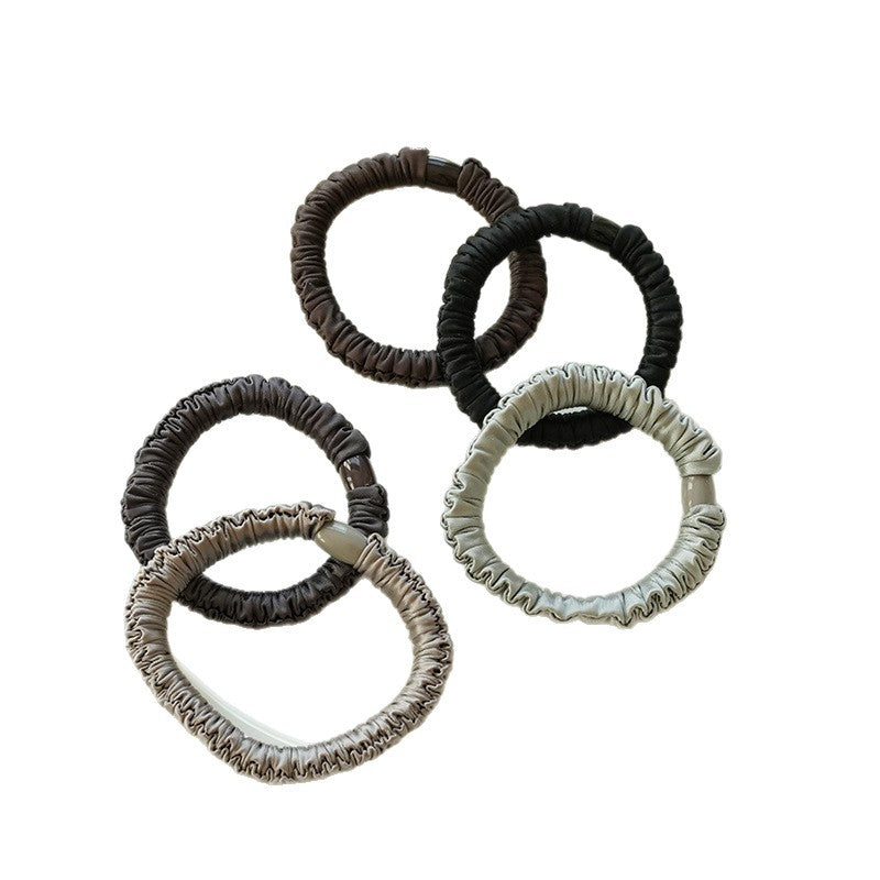 Five gathered fabric hair ties in dark, neutral, and pastel colors