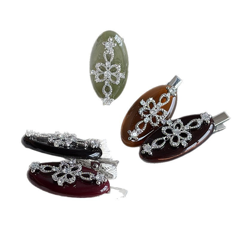Small acetate duckbill hair clip in assorted jewel-toned colors with floral rhinestone decoration