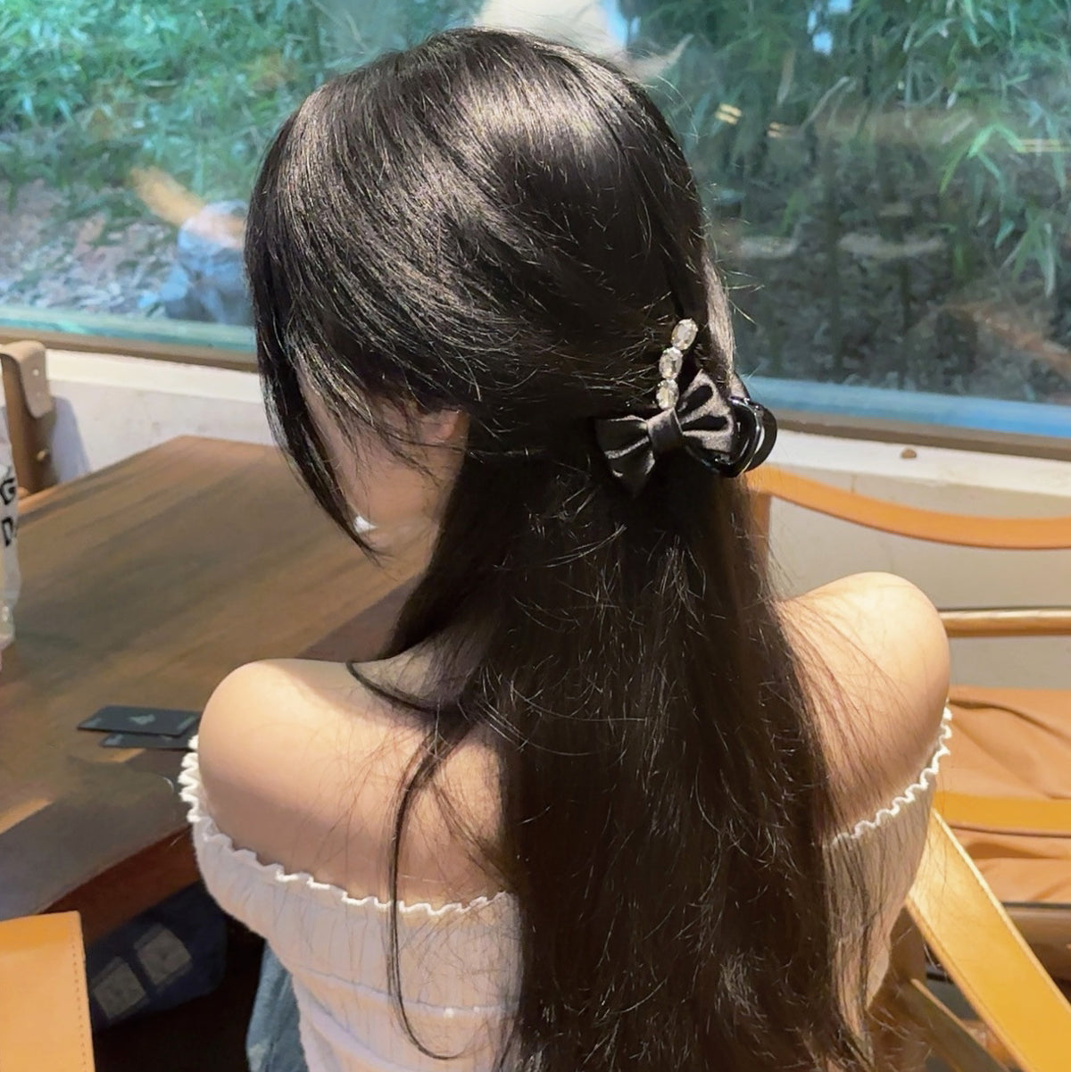 Black bow hair clip worn in a half-up hairstyle
