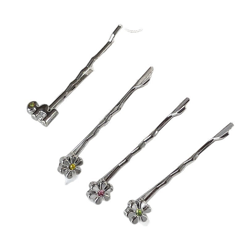 Four silver metal bobby pins with decorative flower and colored rhinestone accents