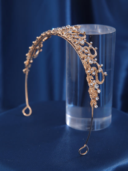 Gold alloy crown with scrolling rhinestone embellishments on blue fabric