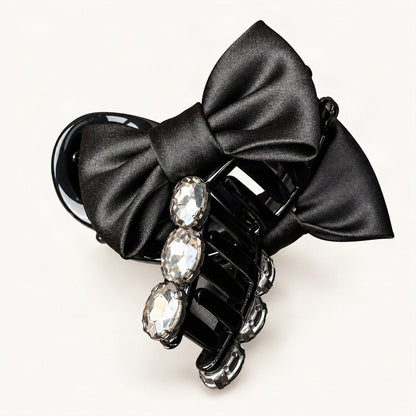 Hand holding black rhinestone bow claw clip to show its details [FITINY Hair]