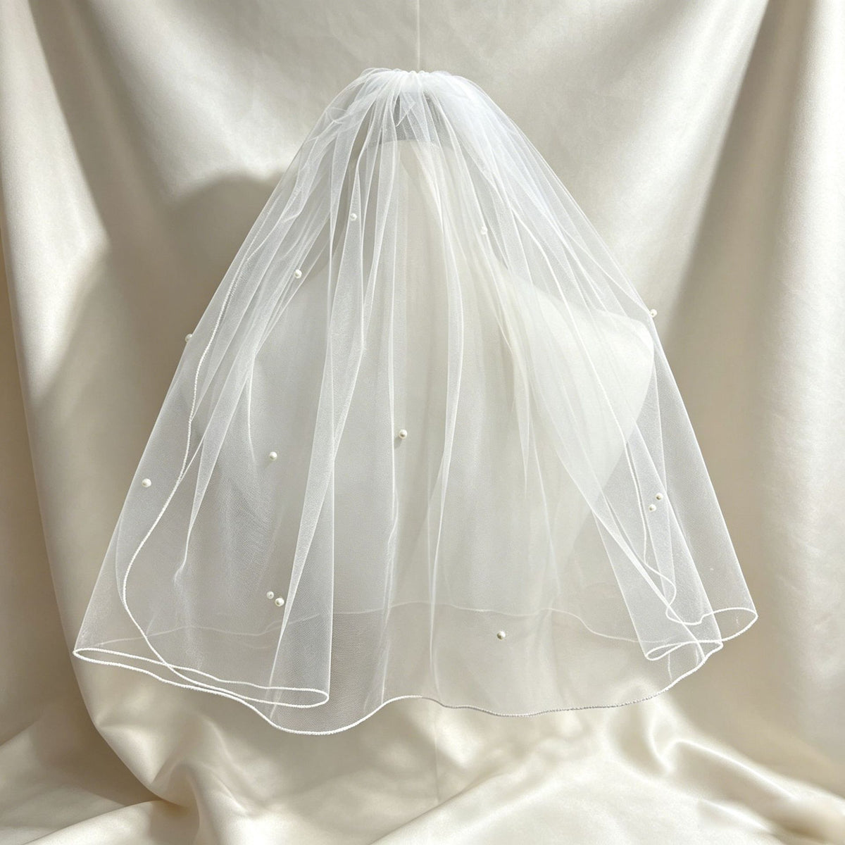 Double-layer pearl bridal veil displayed against a light backdrop