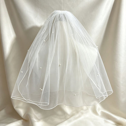 Double-layer pearl bridal veil displayed against a light backdrop