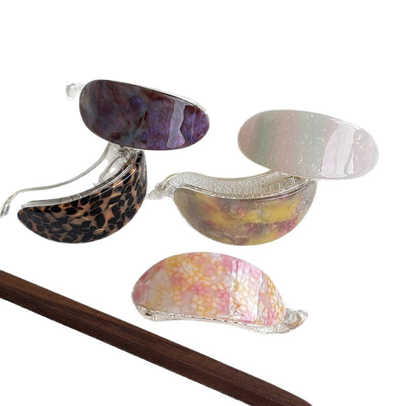 Five colorful acetate hair claw clips in assorted marbled and patterned finishes