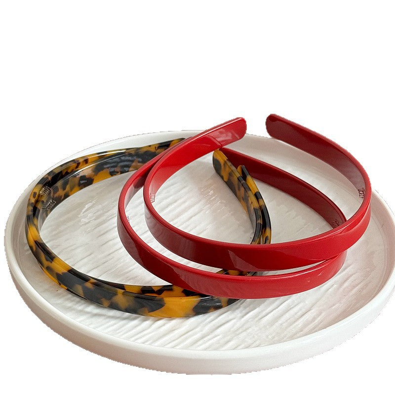 Red and leopard-print acetate headbands arranged on a white dish