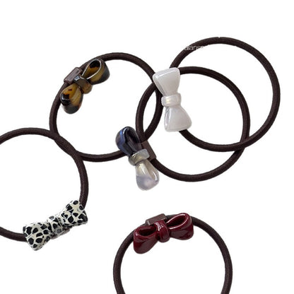 Five polyester hair ties with sculpted acetate bows in assorted colors and patterns