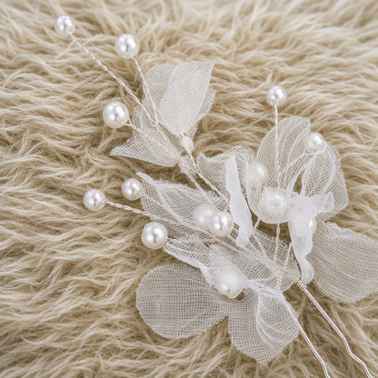 Close-up of sheer organza petals and faux pearl details on a hair pin