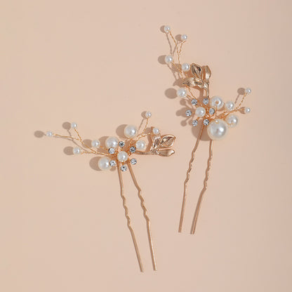 Pair of leaf and faux pearl hair pins arranged on a warm background