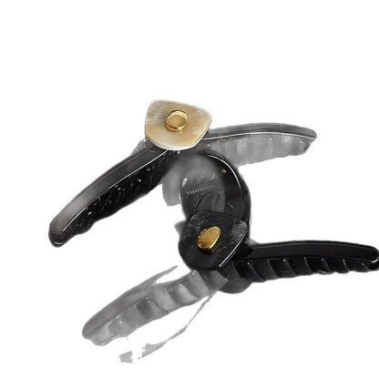 Open acrylic claw clip showing its sculpted teeth and gold-tone decorative accents