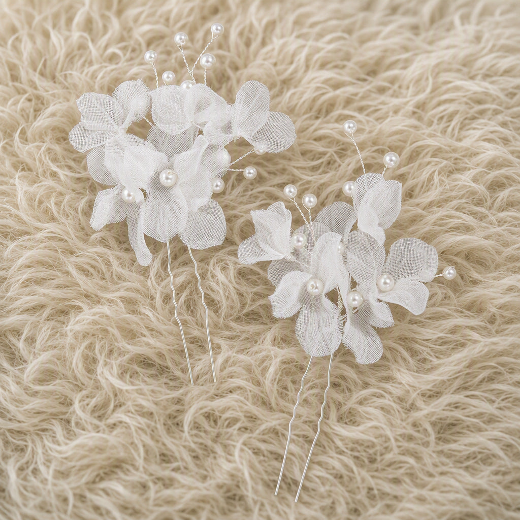 Two white floral bridal hair pins shown from the front