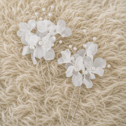 Two white floral bridal hair pins shown from the front