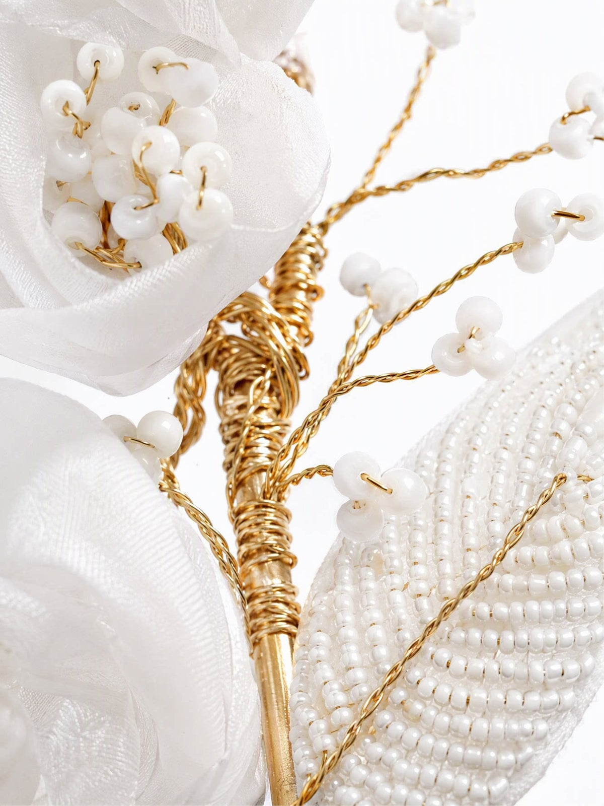 Detail of faux pearl beads, gold-tone wire branches, and mesh petals