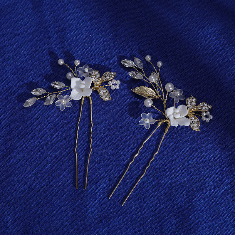Pair of floral hair pins shown on blue fabric