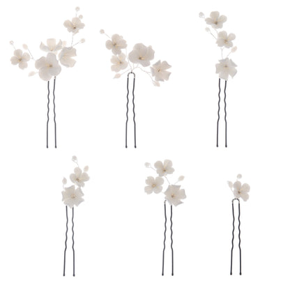 Black wavy U pins with white floral decorations on a plain background