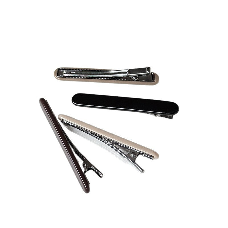 Slim cellulose acetate side hair clips in neutral colors with visible metal hardware