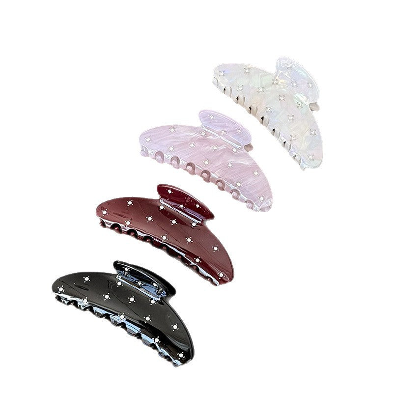 Four acetate claw clips in black, burgundy, purple, and iridescent mermaid colors with scattered rhinestone details
