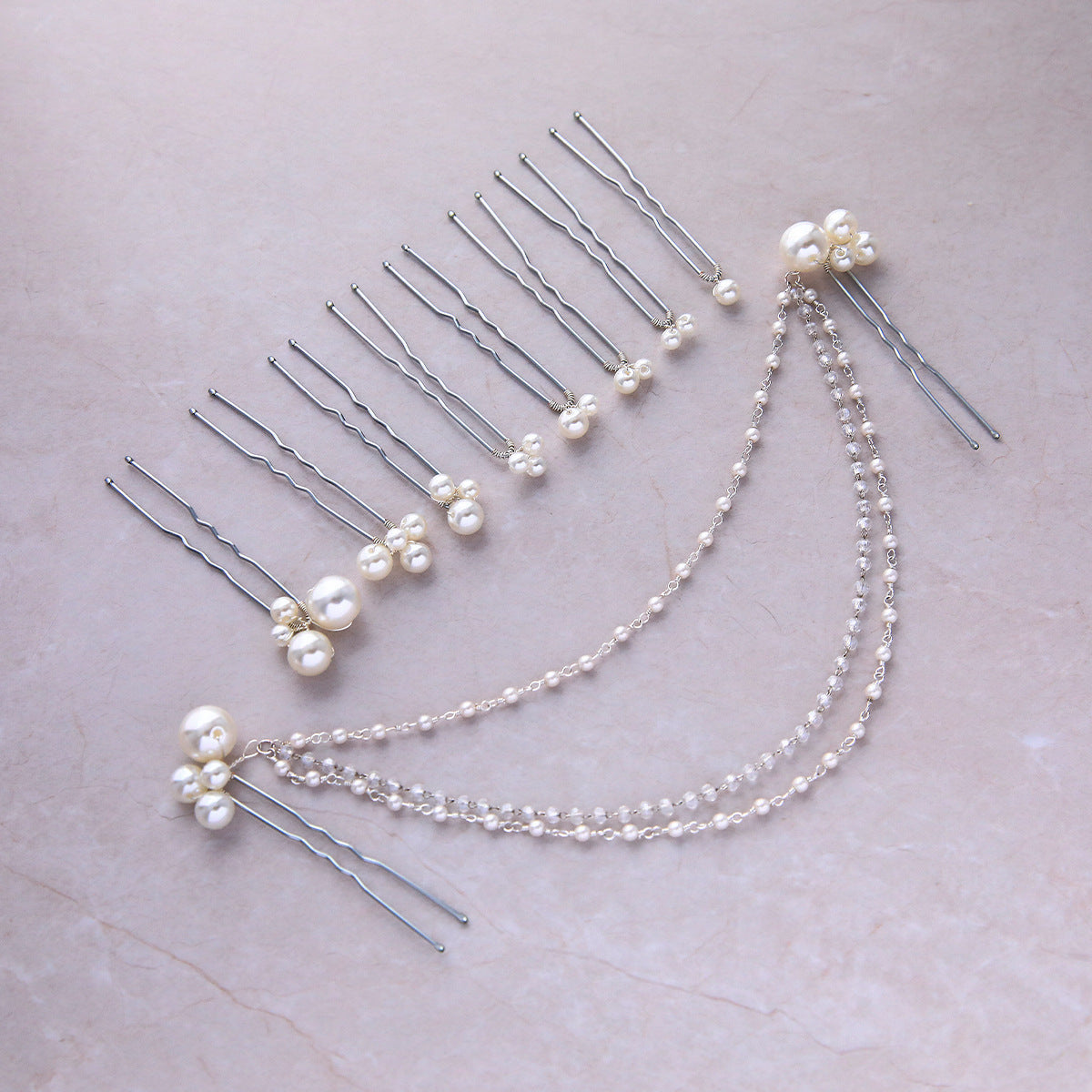 Pearl hair pins and layered beaded chains displayed on a surface
