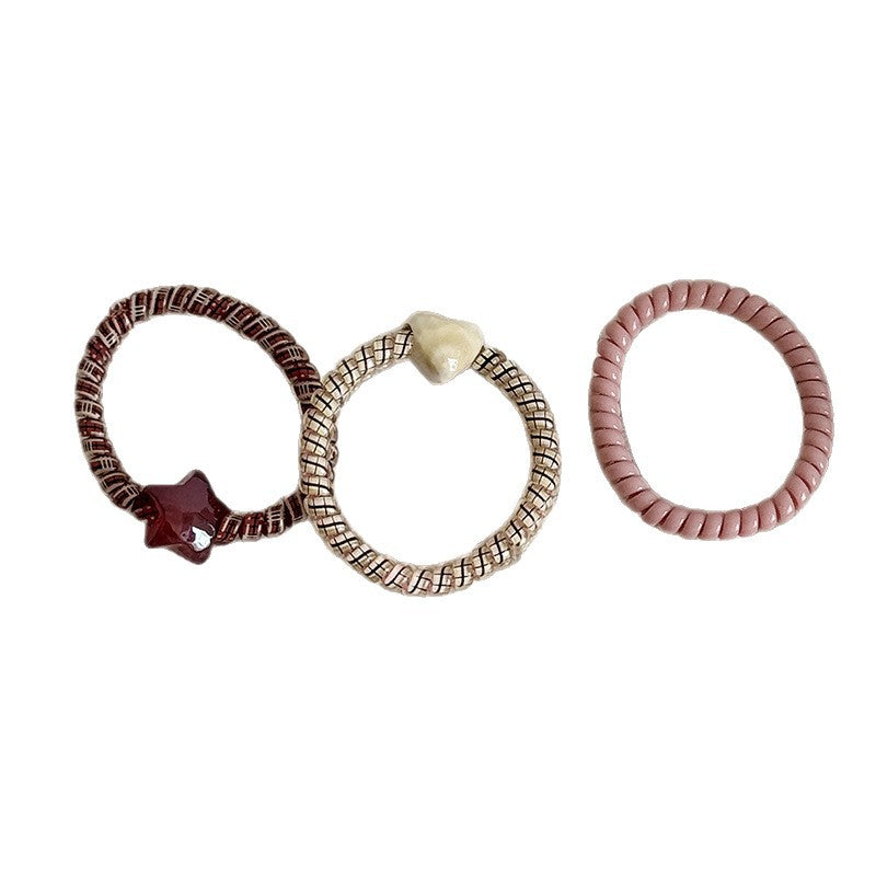 Three decorative stretch hair ties with heart and star charms in assorted colors