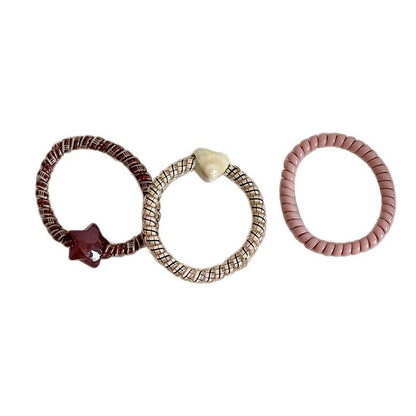 Three decorative stretch hair ties with heart and star charms in assorted colors