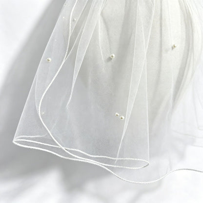 Close-up of sheer veil fabric, faux pearls, and finished edge