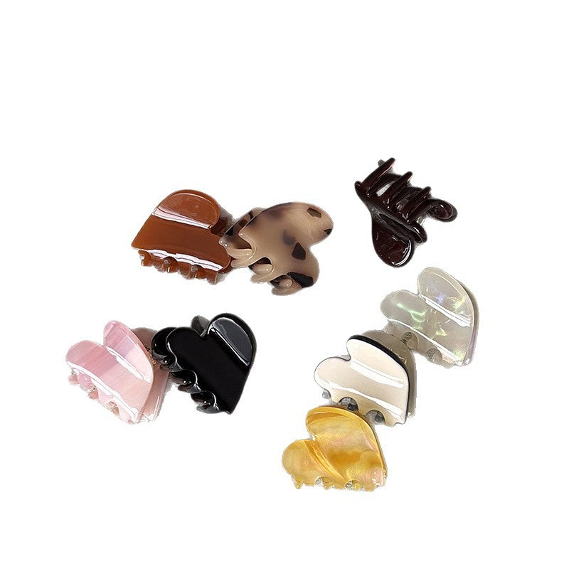 Assorted mini heart claw clips in cellulose acetate, including tortoise, pink, black, cream, and amber styles