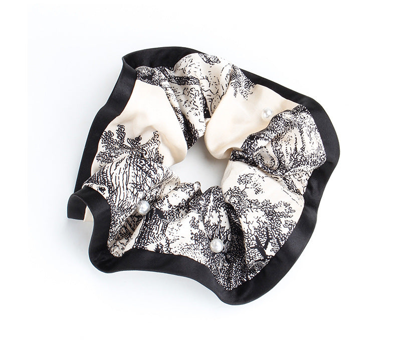 Full view of a gathered marble-print satin scrunchie with pearl accents