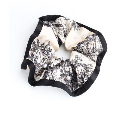 Full view of a gathered marble-print satin scrunchie with pearl accents