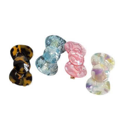 Four acetate bow side hair clips in tortoise, blue floral, shell pink, and multicolor floral finishes